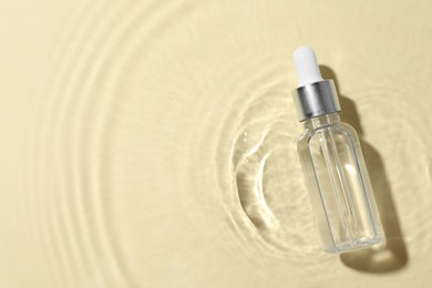 Photo of Bottle of cosmetic oil in water on beige background, top view. Space for text