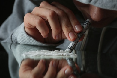 Photo of Drug addict taking cocaine at table, closeup view