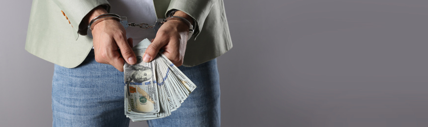 Image of Man in handcuffs holding bribe on grey background, closeup with space for text. Banner design