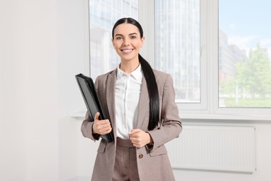 Beautiful real estate agent with documents indoors