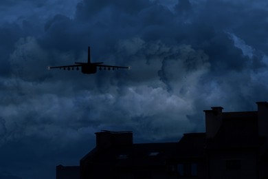 Image of Silhouette of jet fighter in cloudy sky at night