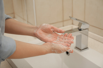 Photo of Woman washing hands with antiseptic soap in bathroom, closeup. Virus prevention