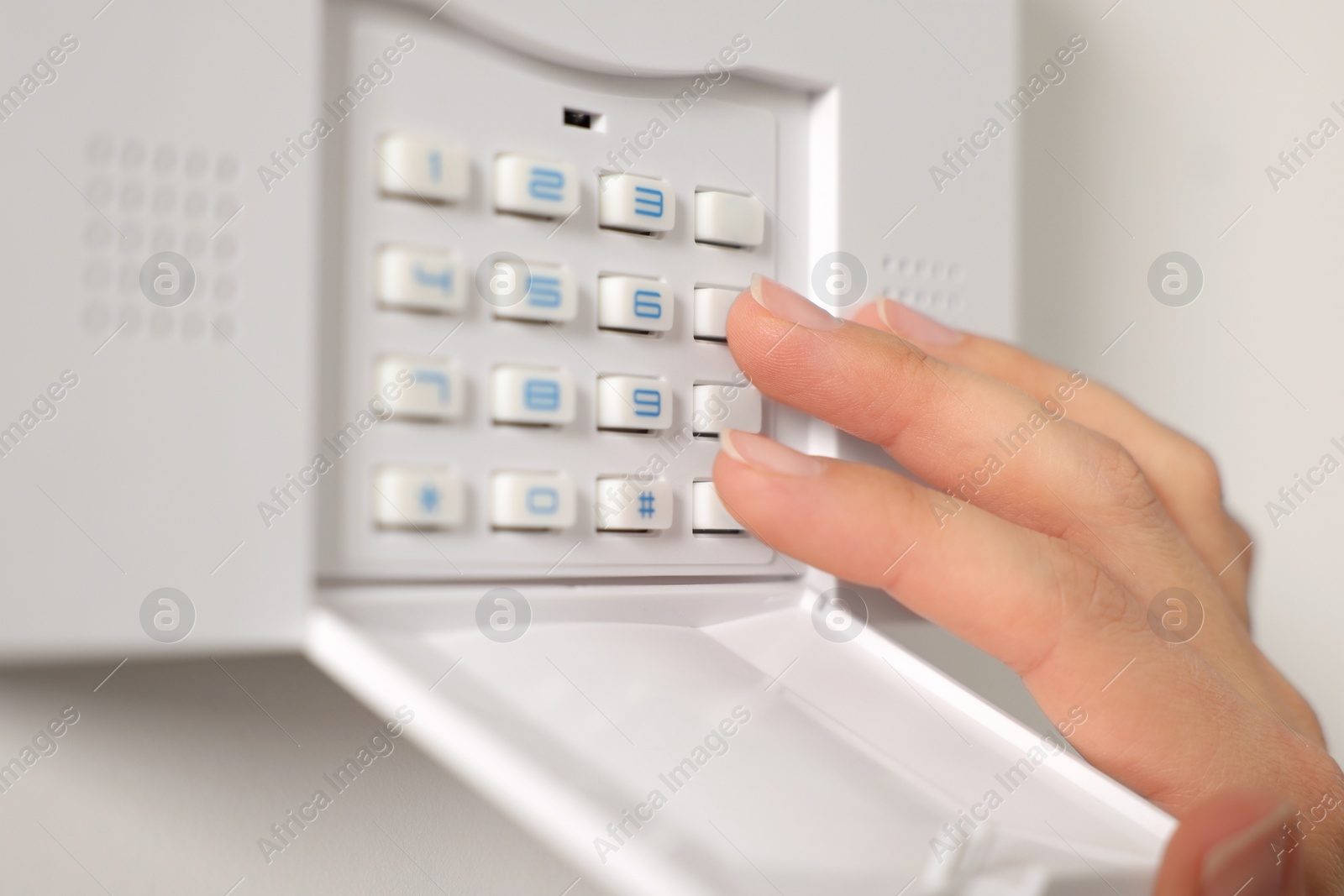 Photo of Woman entering code on security system, closeup