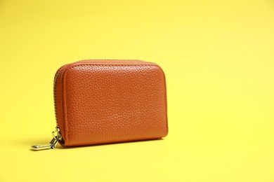 Stylish brown leather purse on yellow background. Space for text