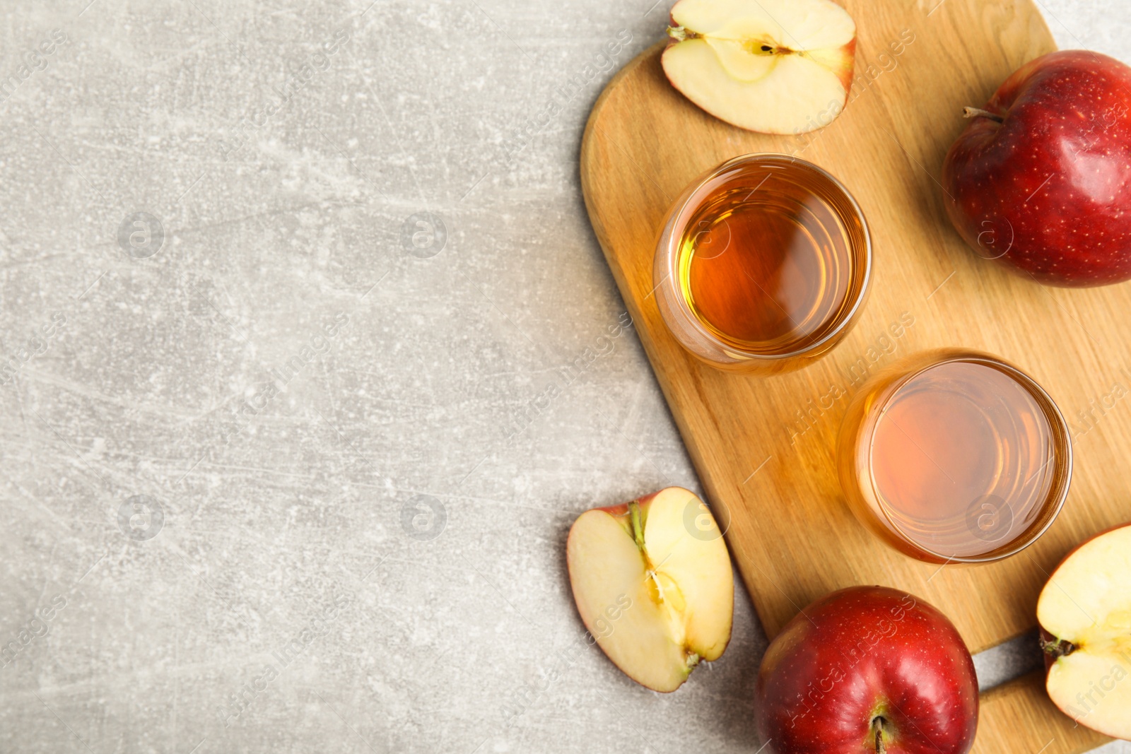 Photo of Delicious cider and ripe red apples on light grey table, flat lay. Space for text