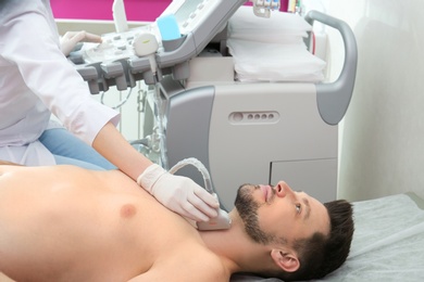 Photo of Doctor conducting ultrasound examination of thyroid gland in clinic