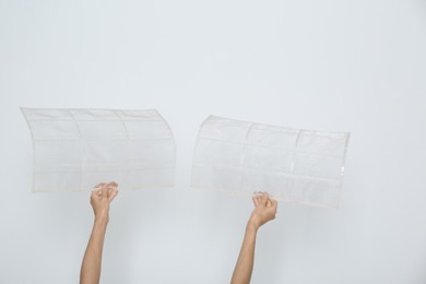 Photo of Woman holding air conditioner filters near white wall, closeup