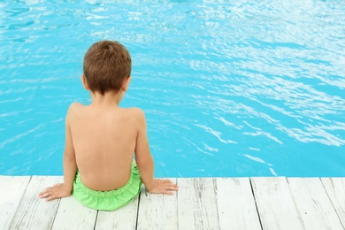 Photo of Little child near outdoor swimming pool. Dangerous situation