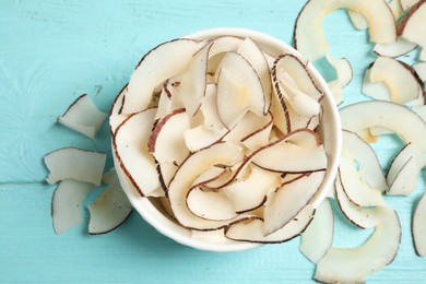 Tasty coconut chips on light blue wooden table, flat lay