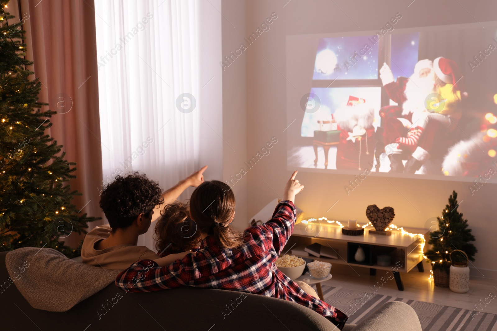 Photo of Family watching Christmas movie via video projector at home