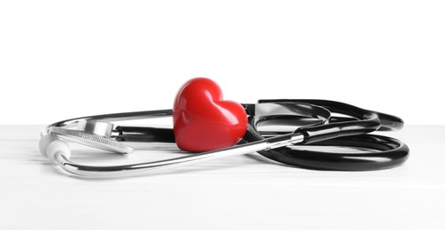 Photo of Stethoscope and red heart on wooden table against white background