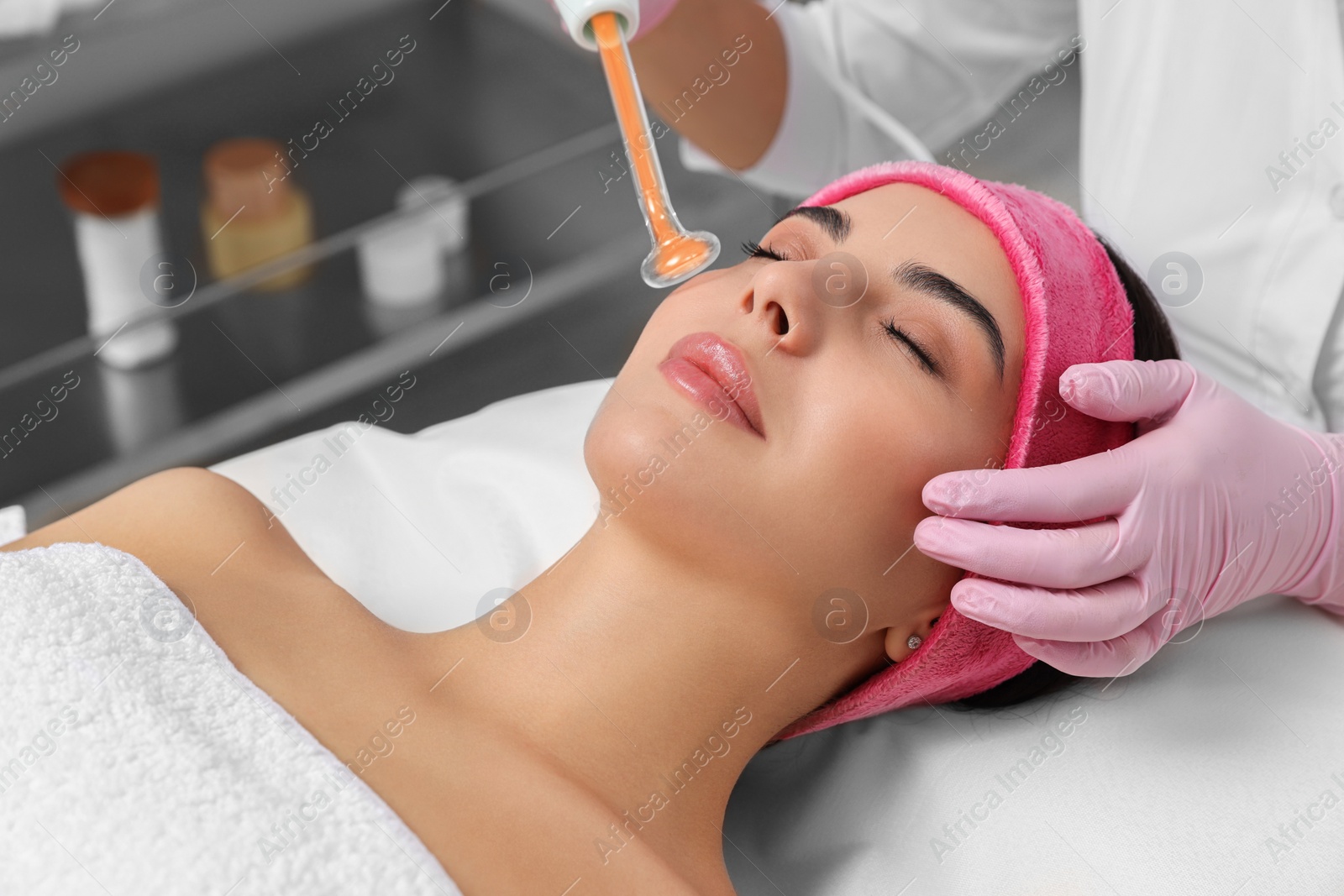 Photo of Young woman undergoing face rejuvenation procedure with darsonval in salon