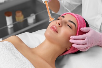 Photo of Young woman undergoing face rejuvenation procedure with darsonval in salon