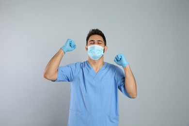 Emotional doctor with protective mask on light grey background. Strong immunity concept