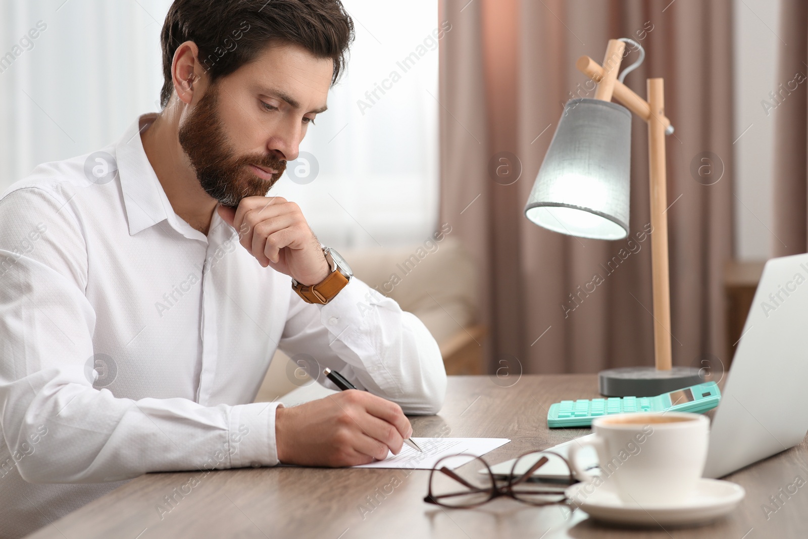 Photo of Businessman working with documents at wooden table in office