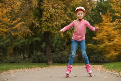 Photo of Cute girl roller skating in autumn park. Space for text