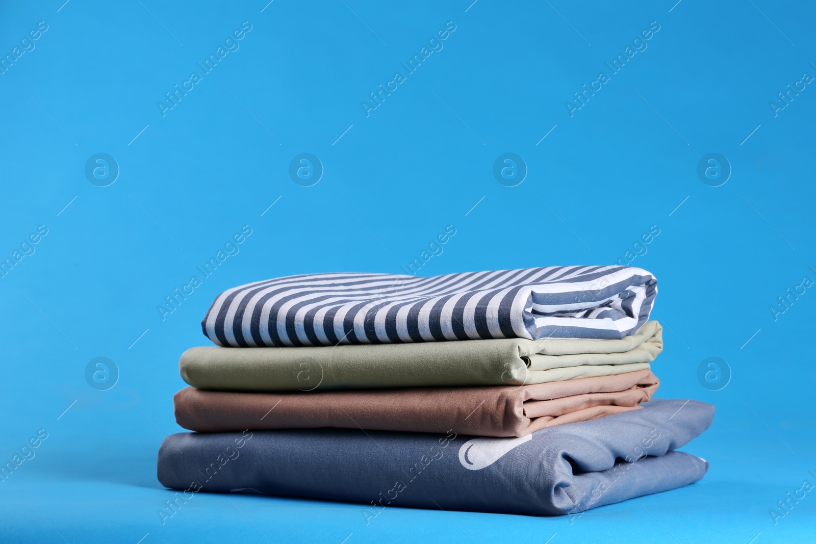 Photo of Stack of clean bed sheets on blue background