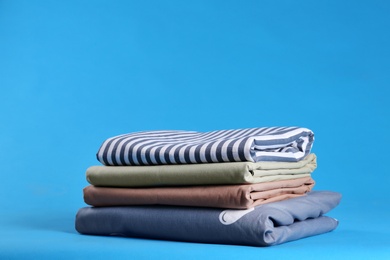 Stack of clean bed sheets on blue background