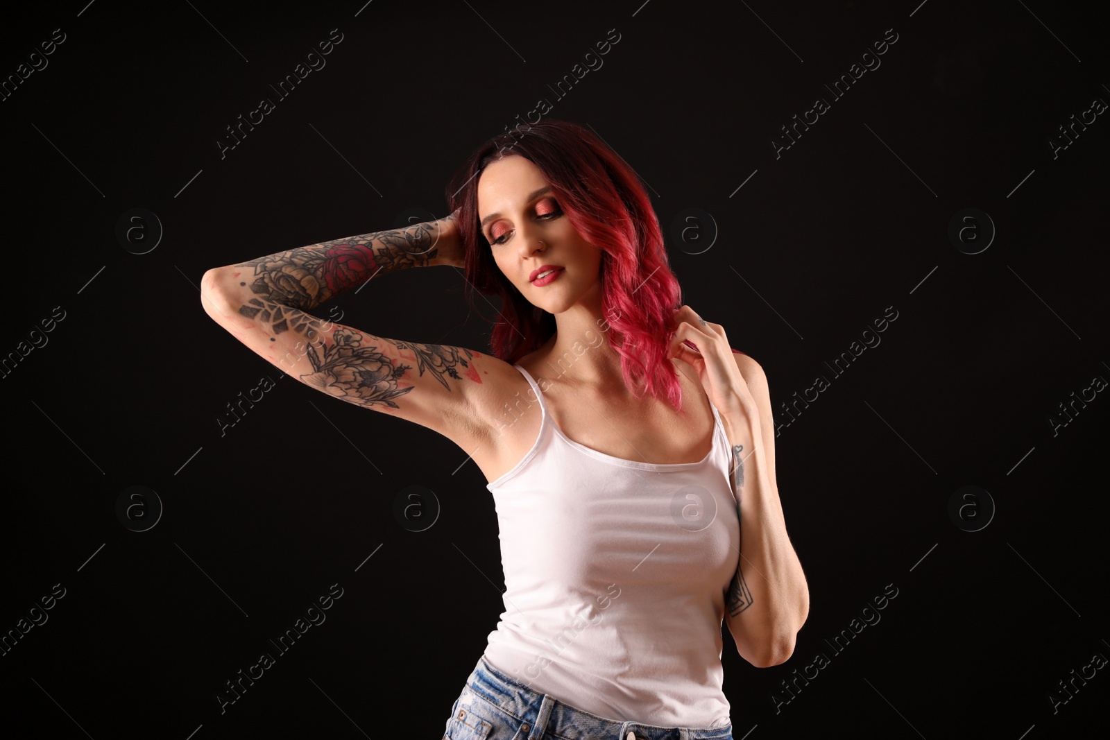 Photo of Beautiful woman with tattoos on arms against black background