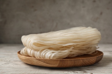 Photo of Plate with raw rice noodles on wooden table