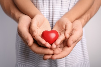 Family holding small red heart in hands together, closeup