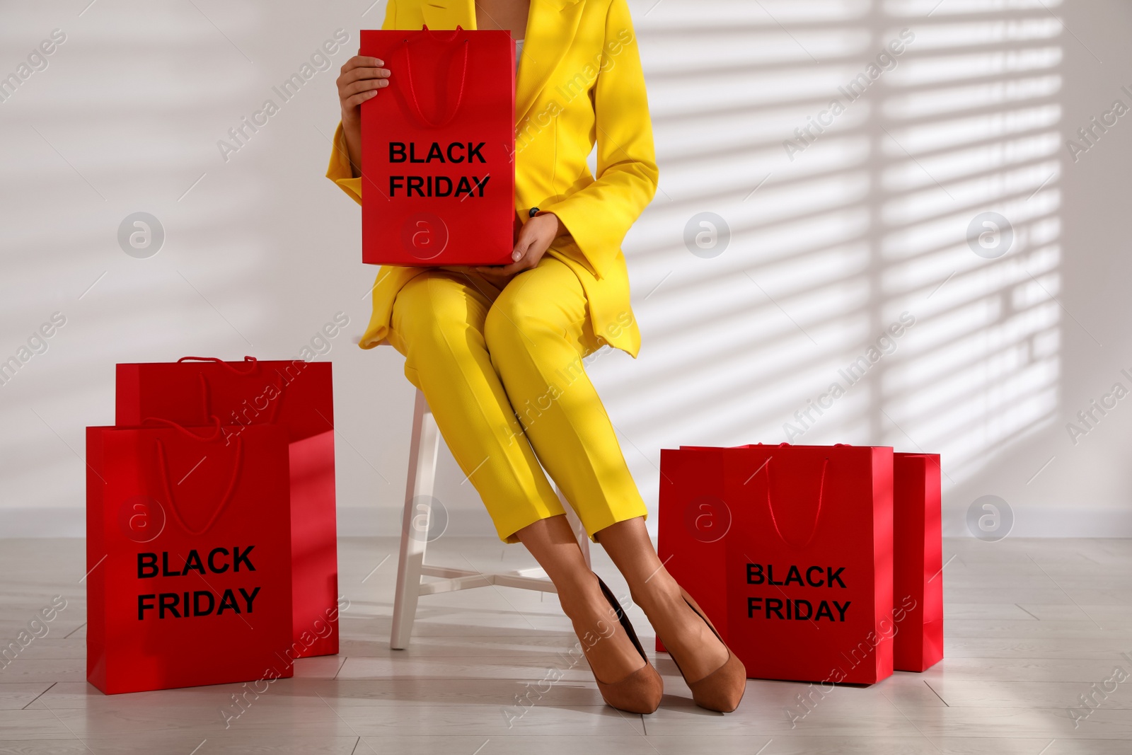 Photo of Woman with shopping bags sitting on stool, closeup. Black Friday