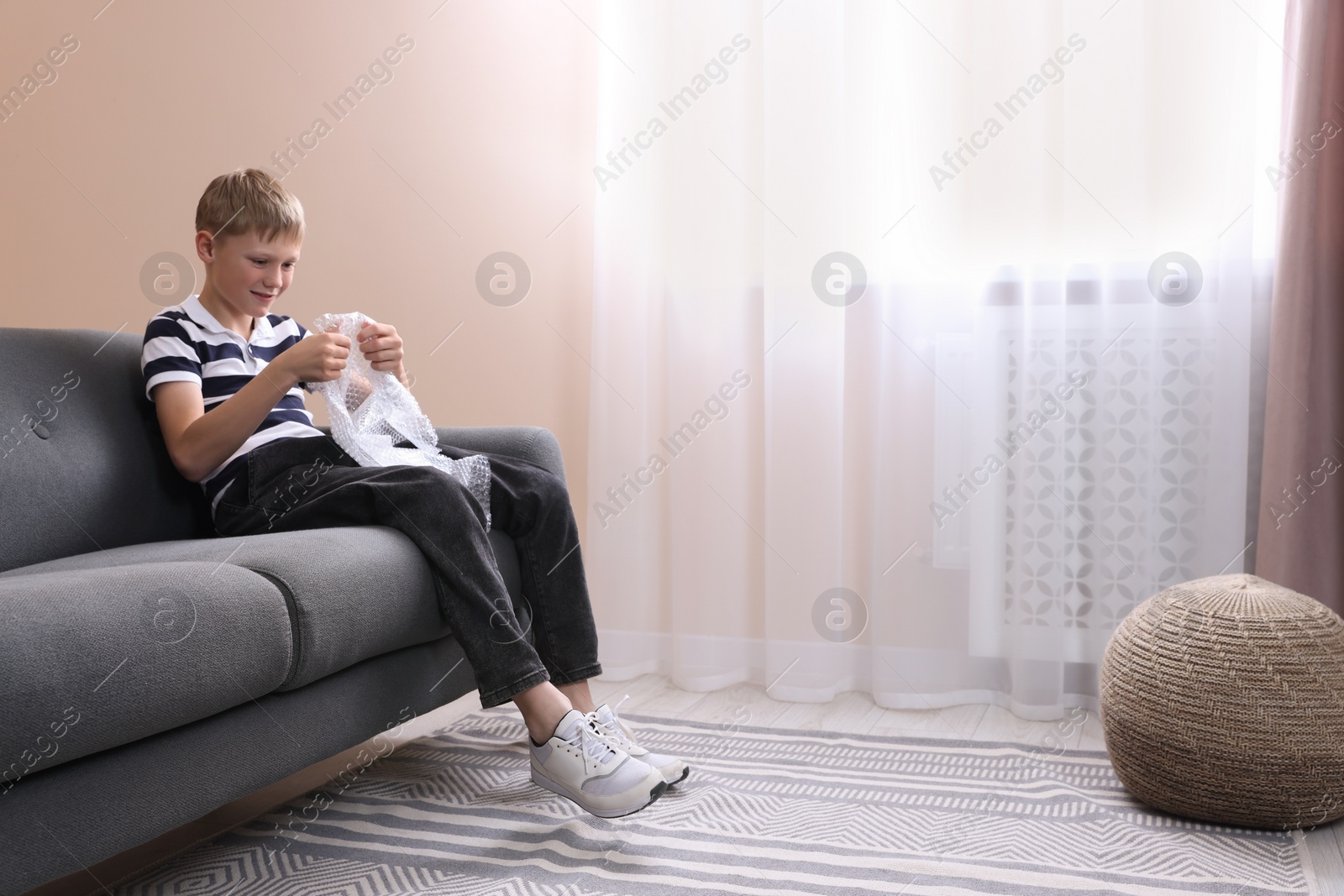 Photo of Boy popping bubble wrap at home, space for text. . Stress relief