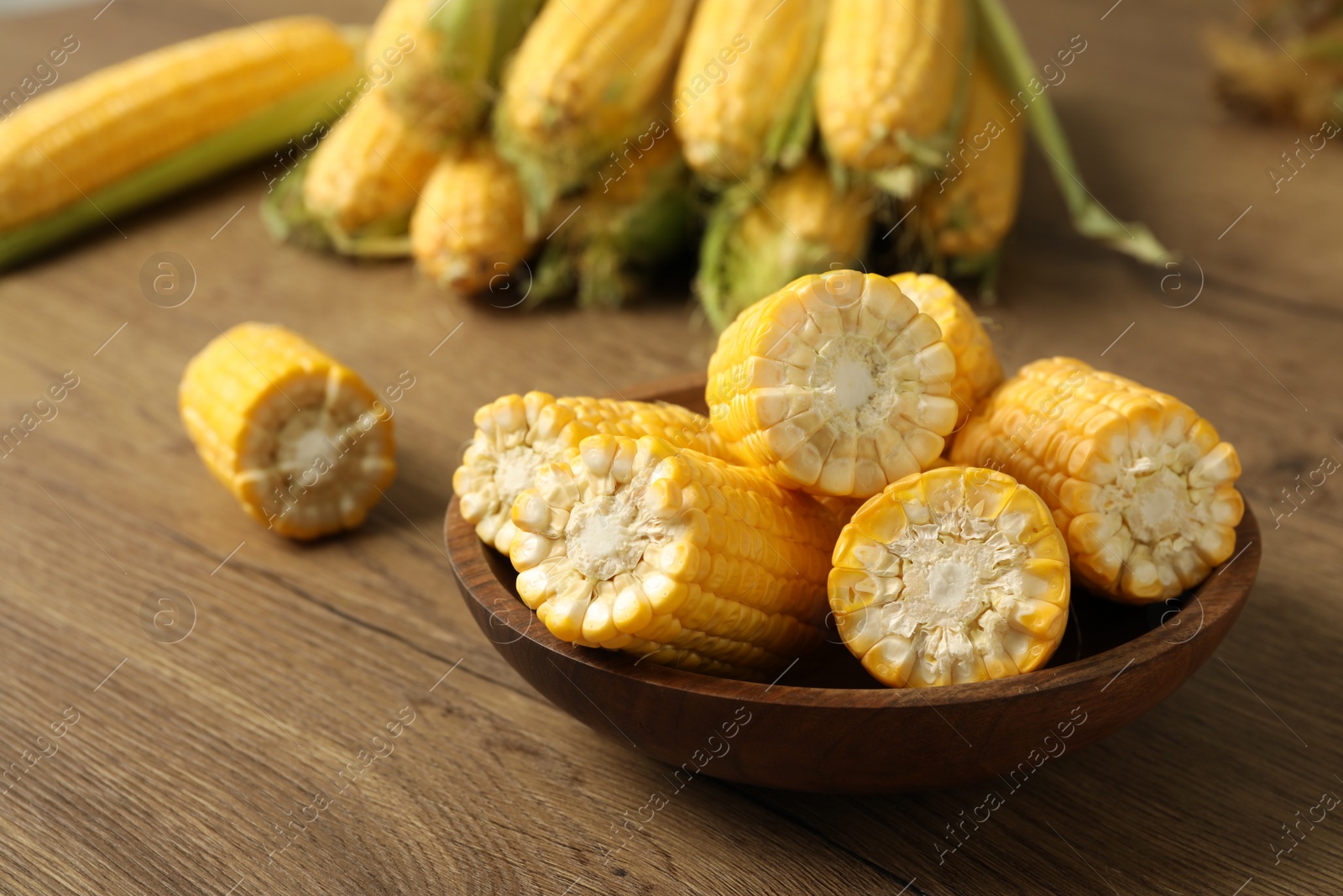 Photo of Tasty sweet corn cobs on wooden table, closeup