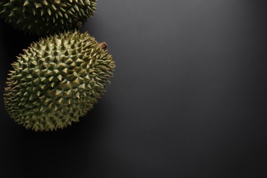 Photo of Fresh ripe durians on black background, flat lay. Space for text