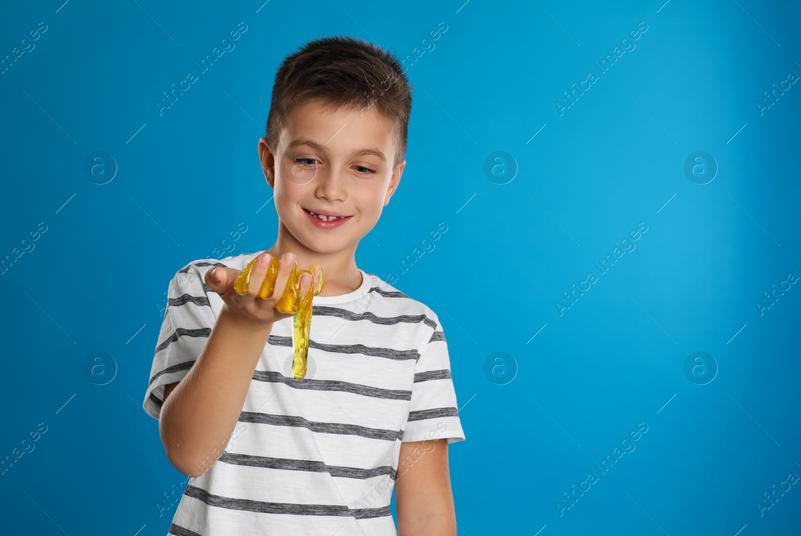 Photo of Little boy with slime on blue background, space for text