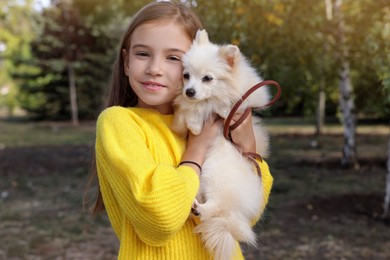 Photo of Little girl with her cute dog in park. Autumn walk