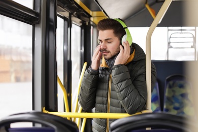 Photo of Young man listening to music with headphones in public transport