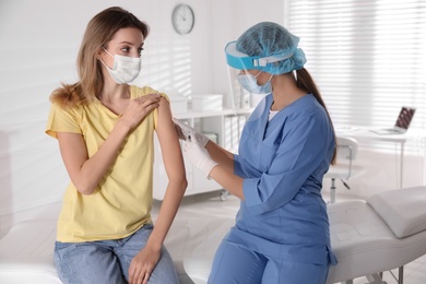 Photo of Doctor vaccinating young woman against Covid-19 in clinic