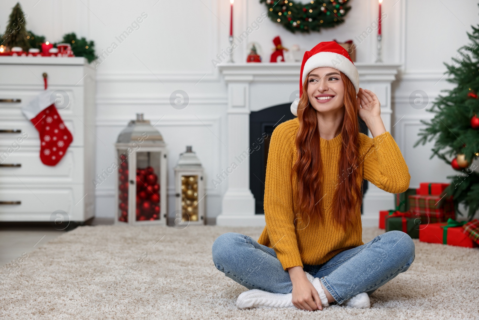 Photo of Beautiful young woman wearing Santa hat in room decorated for Christmas