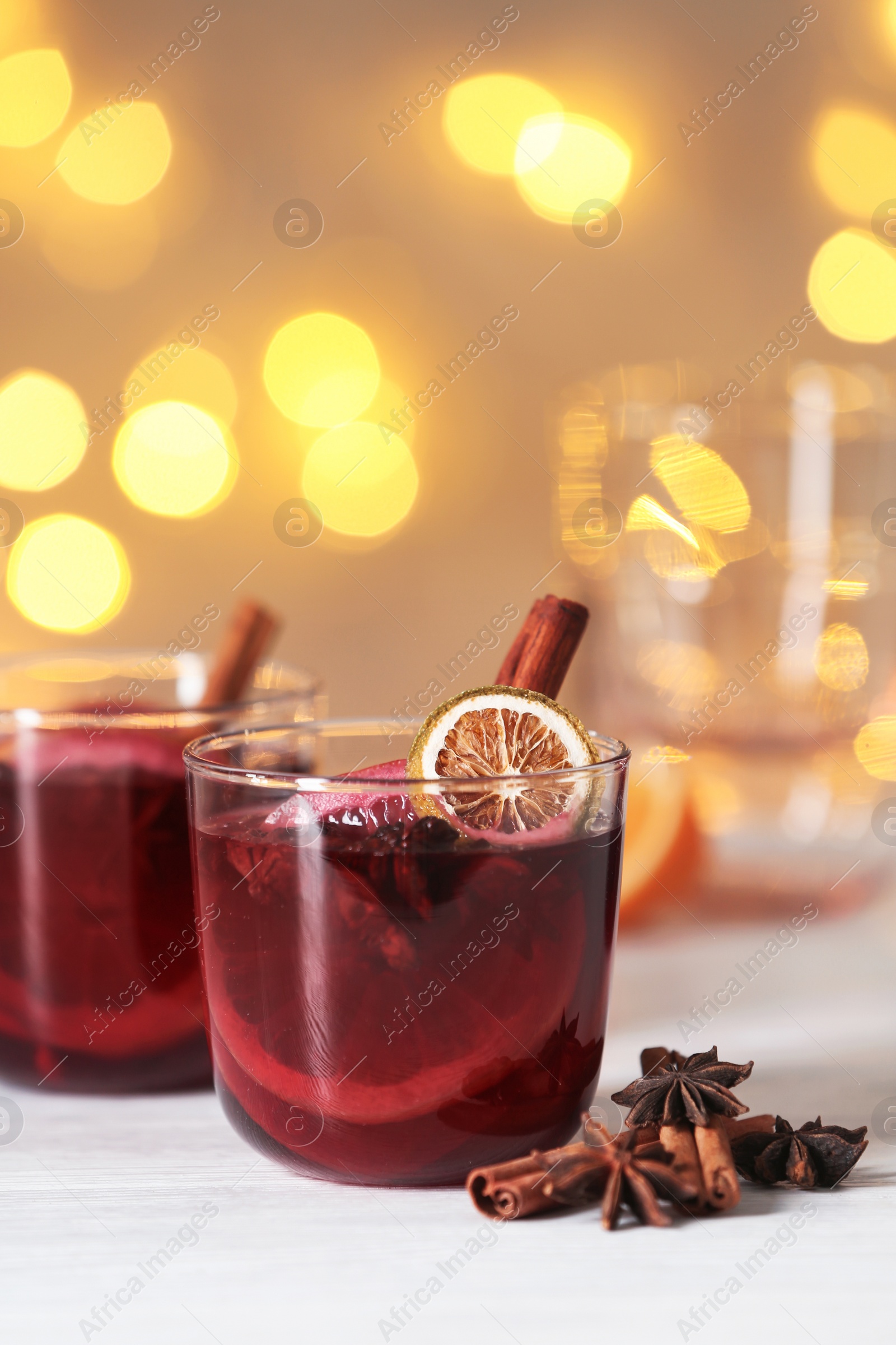 Photo of Glasses with mulled wine on table against blurred background