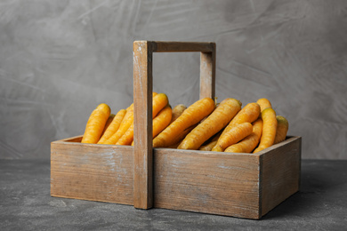 Photo of Raw yellow carrots in basket on wooden table