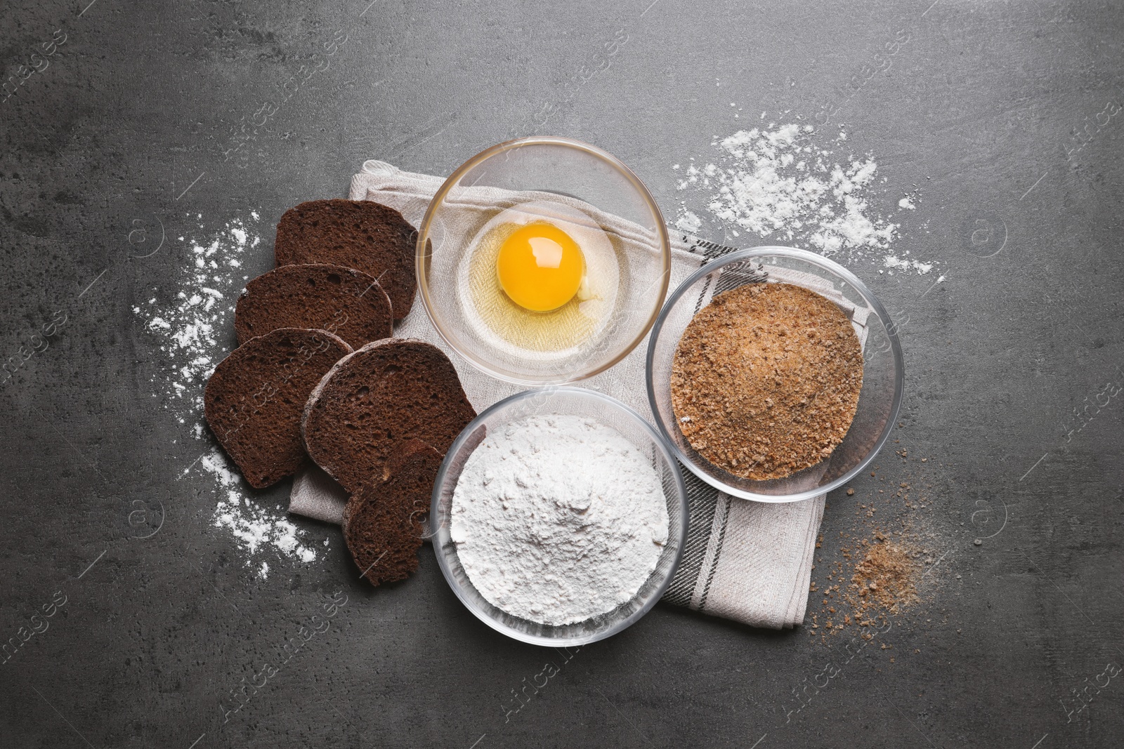 Photo of Fresh breadcrumbs, flour and egg on grey table, flat lay