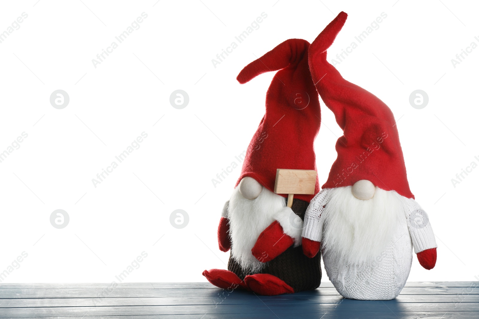 Photo of Funny Christmas gnomes on blue wooden table against white background. Space for text