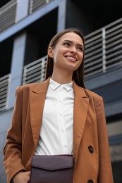 Photo of Young woman in formal clothes near building outdoors