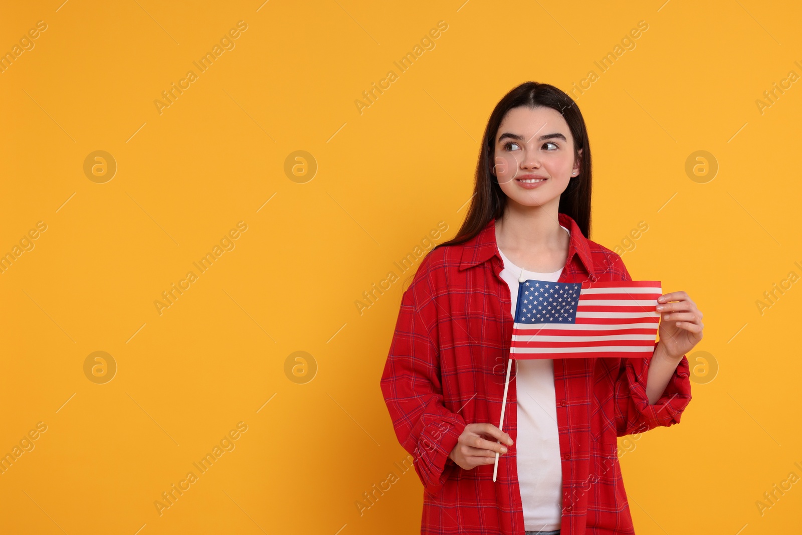 Photo of 4th of July - Independence Day of USA. Happy girl with American flag on yellow background, space for text