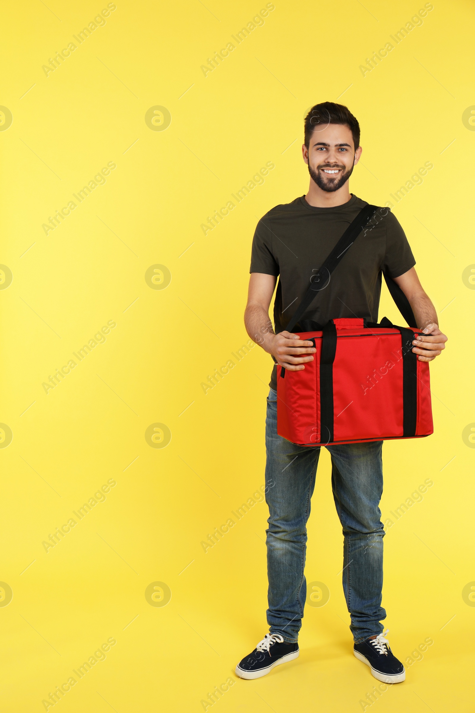 Photo of Young courier with thermo bag on color background, space for text. Food delivery service