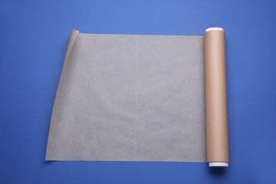 Photo of Roll of baking paper on blue background, top view