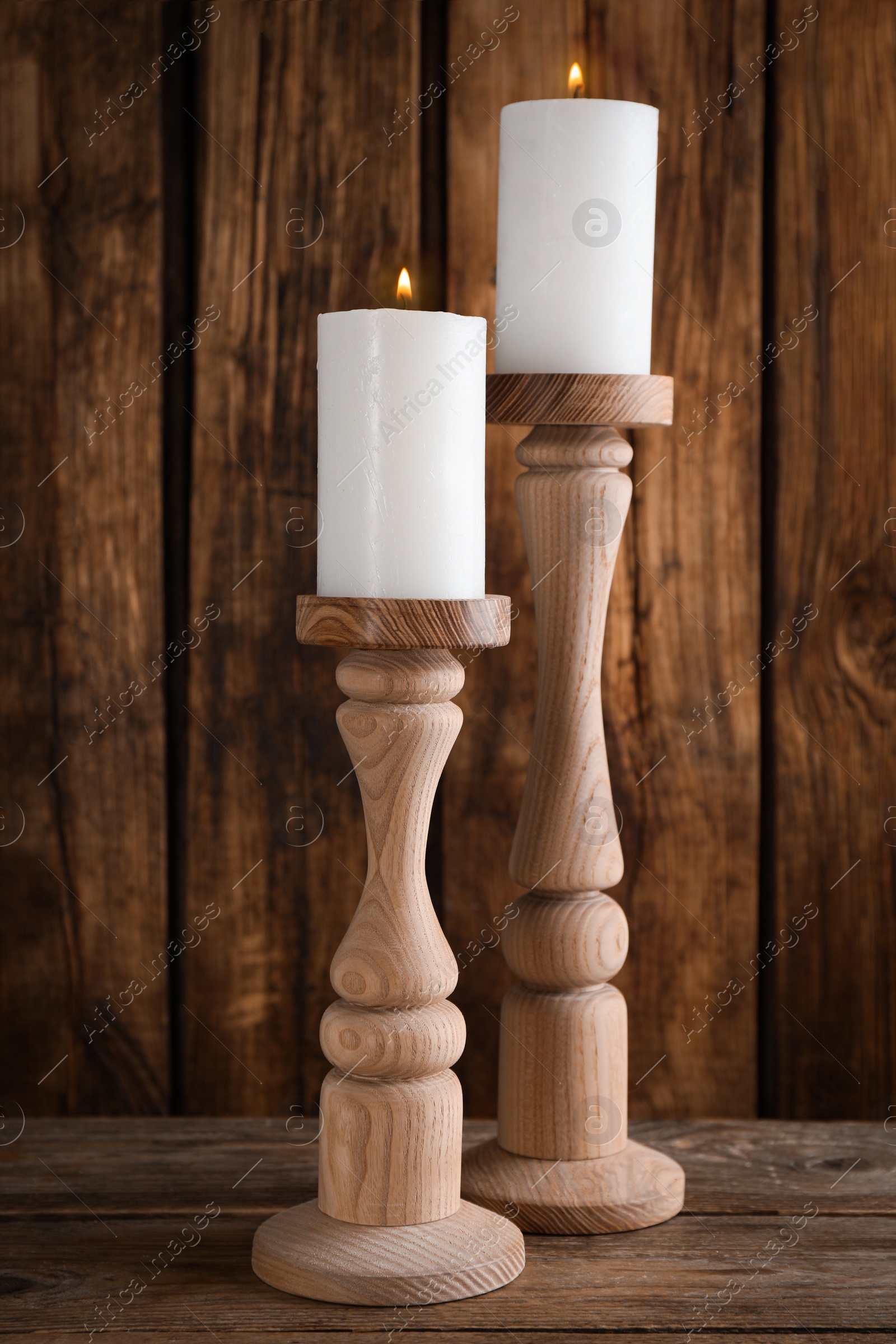 Photo of Elegant candlesticks with burning candles on wooden table