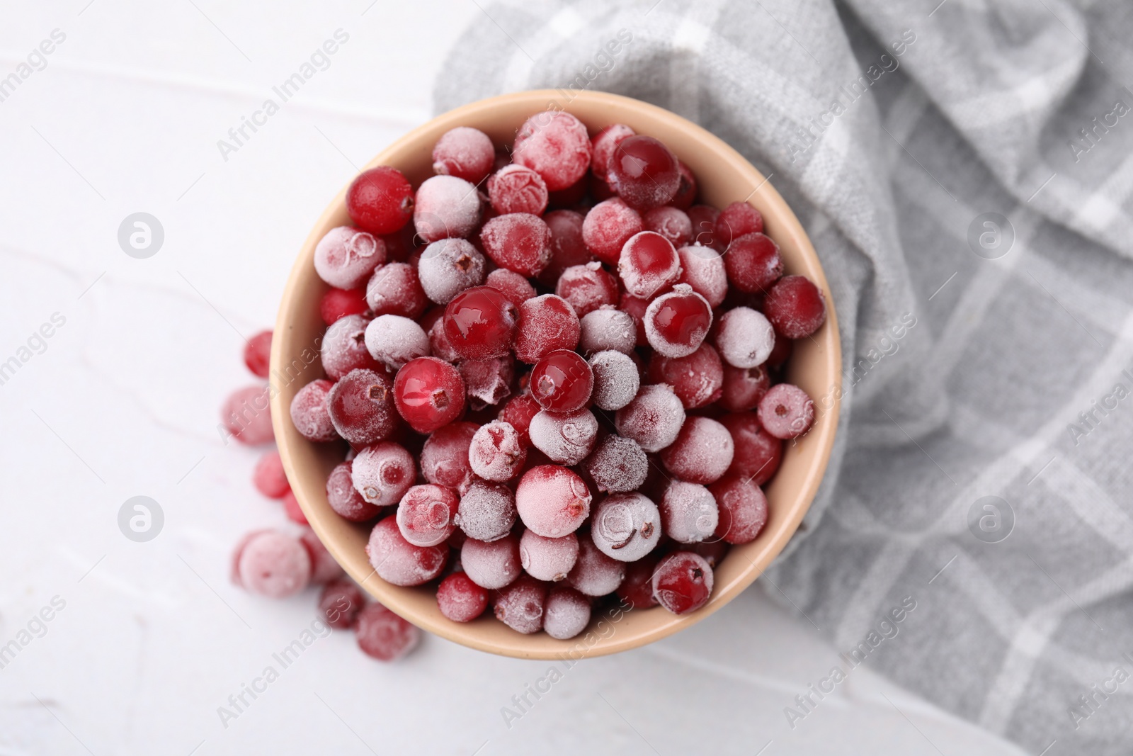 Photo of Frozen red cranberries in bowl on white table, top view