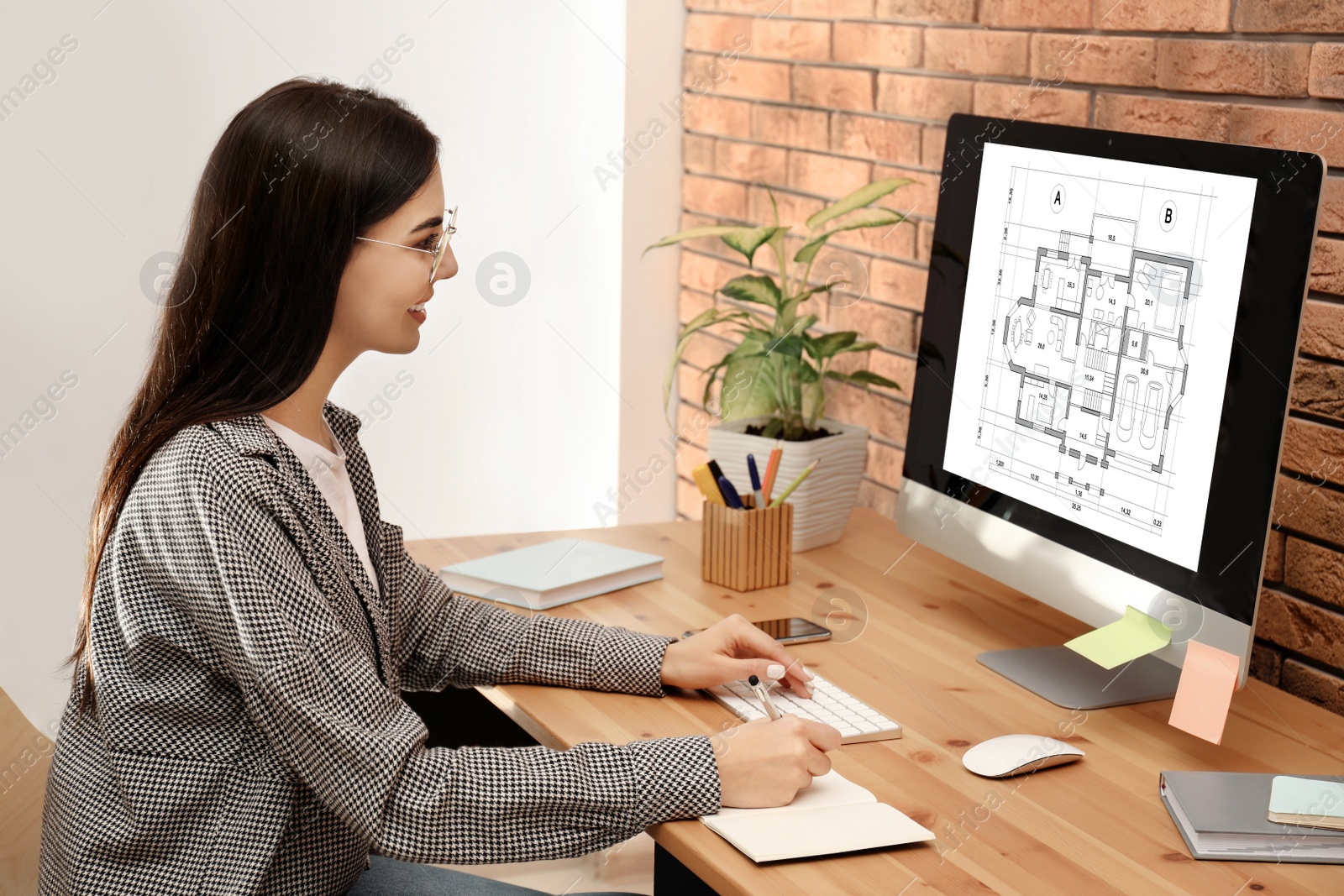 Image of Young architect making project of house on computer in office