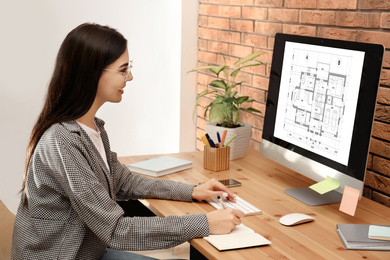 Image of Young architect making project of house on computer in office