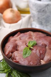 Photo of Bowl with raw chicken liver and basil on table, closeup