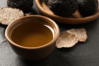 Photo of Bowl of truffle oil on grey table, closeup
