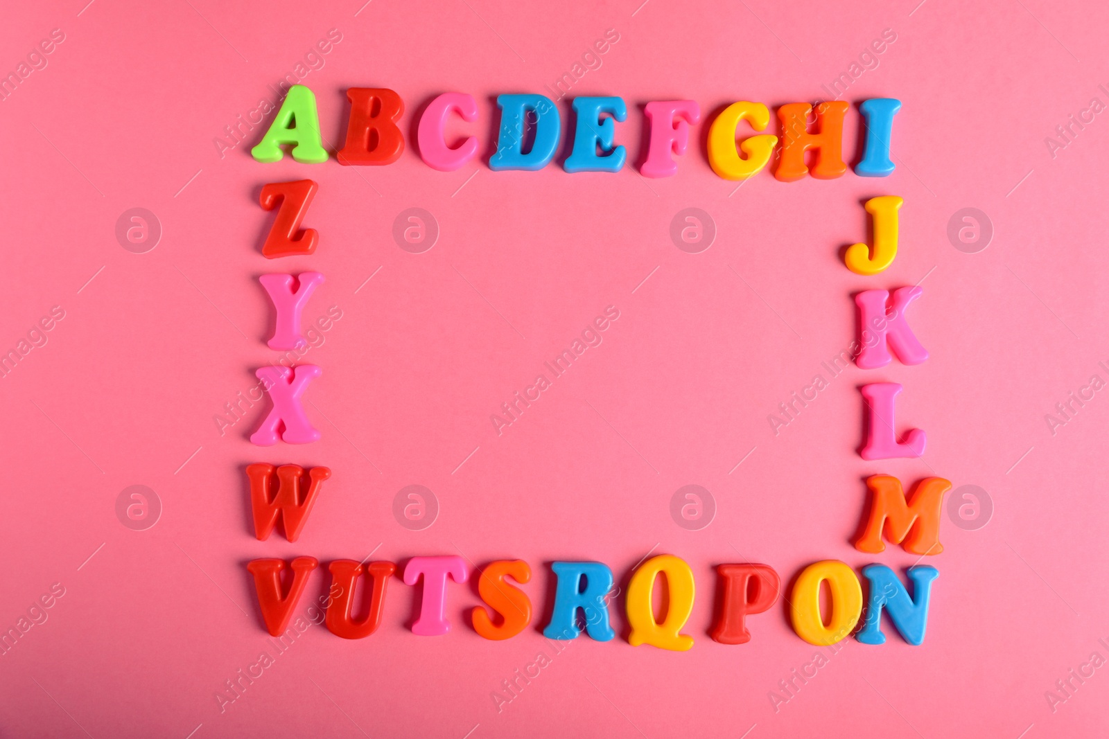 Photo of Frame made of many colorful magnetic letters on pink background, flat lay with space for text