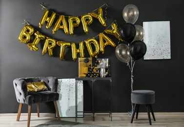 Photo of Room interior with gift boxes and phrase HAPPY BIRTHDAY made of golden balloon letters